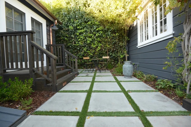 A black wood deck leads down to a concrete paver patio