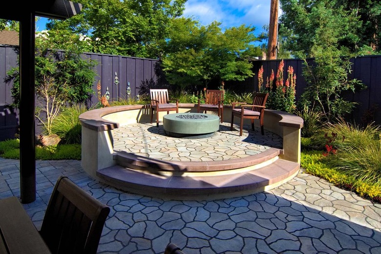 A raised circular stone patio features a fire pit