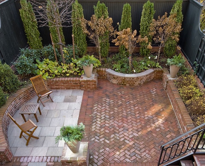 A patio has both brick herringbone and concrete pavers