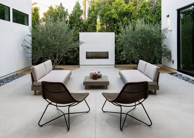 A white concrete outdoor fireplace is the centerpiece of this modern patio