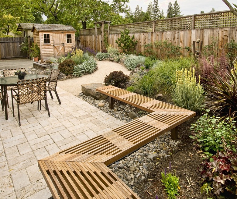 A decorative wooden bench frames a stamped concrete patio