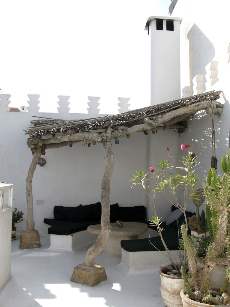 A desert-chic hardscape design with a wooden pergola and built-in benches