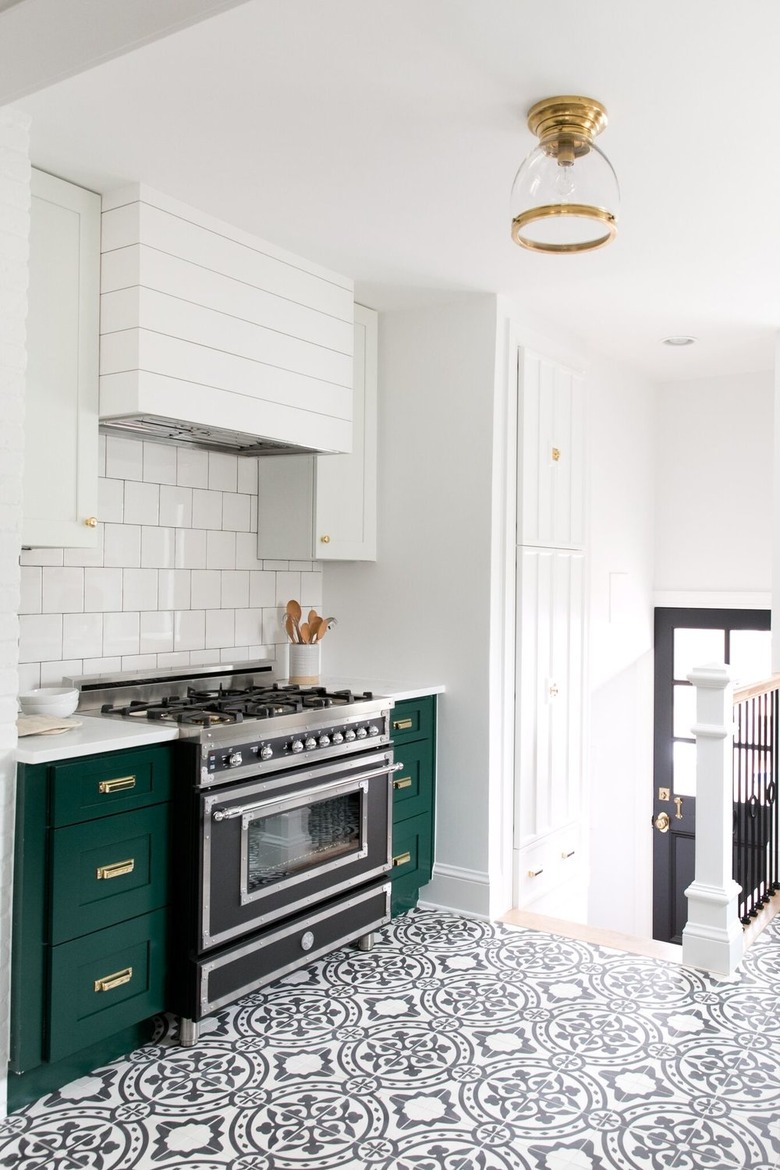 green kitchen cabinets with patterned floor tile an white walls
