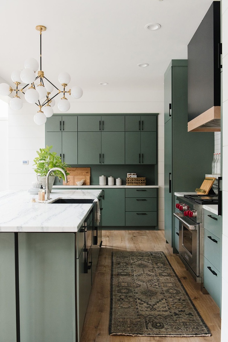 green kitchen cabinets with green backsplash and area rug