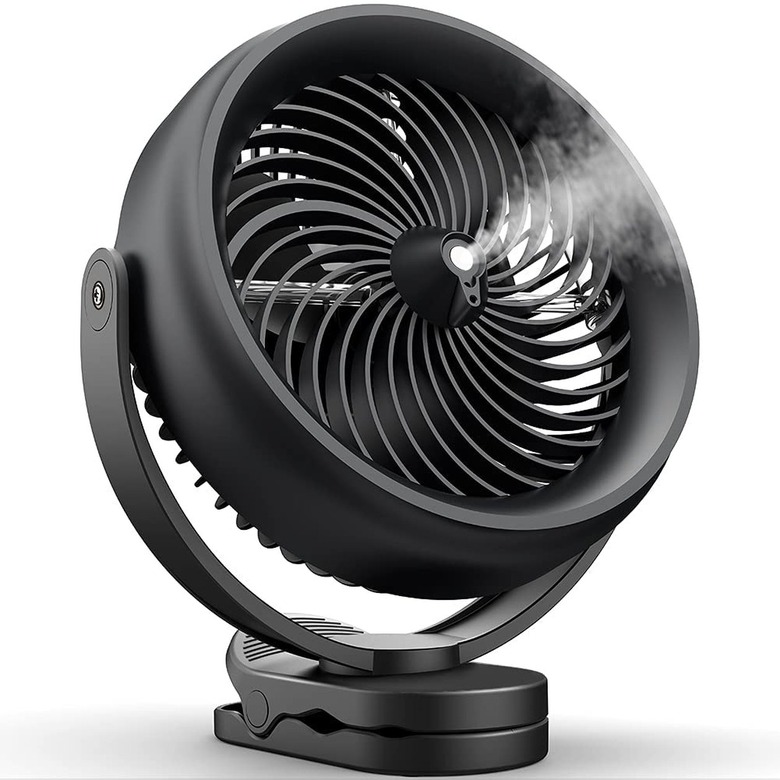 Black circular table fan blowing mist