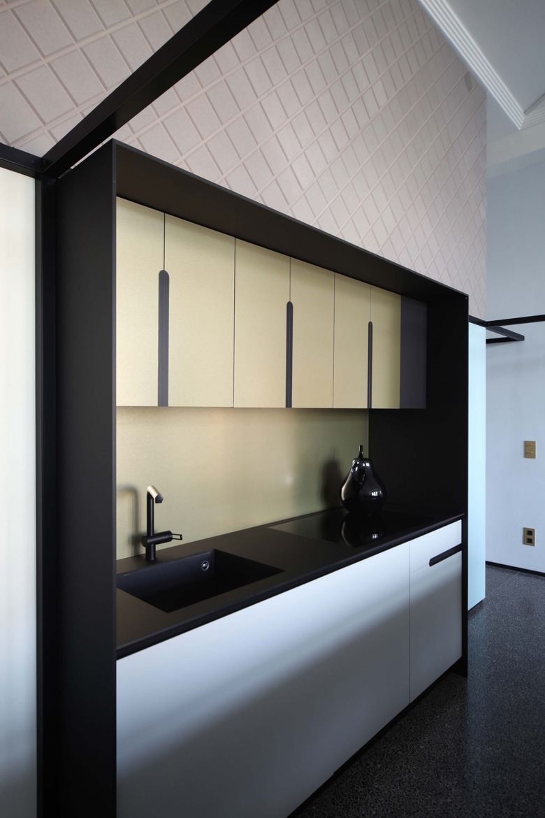sleek kitchen with black countertops and yellow cabinets