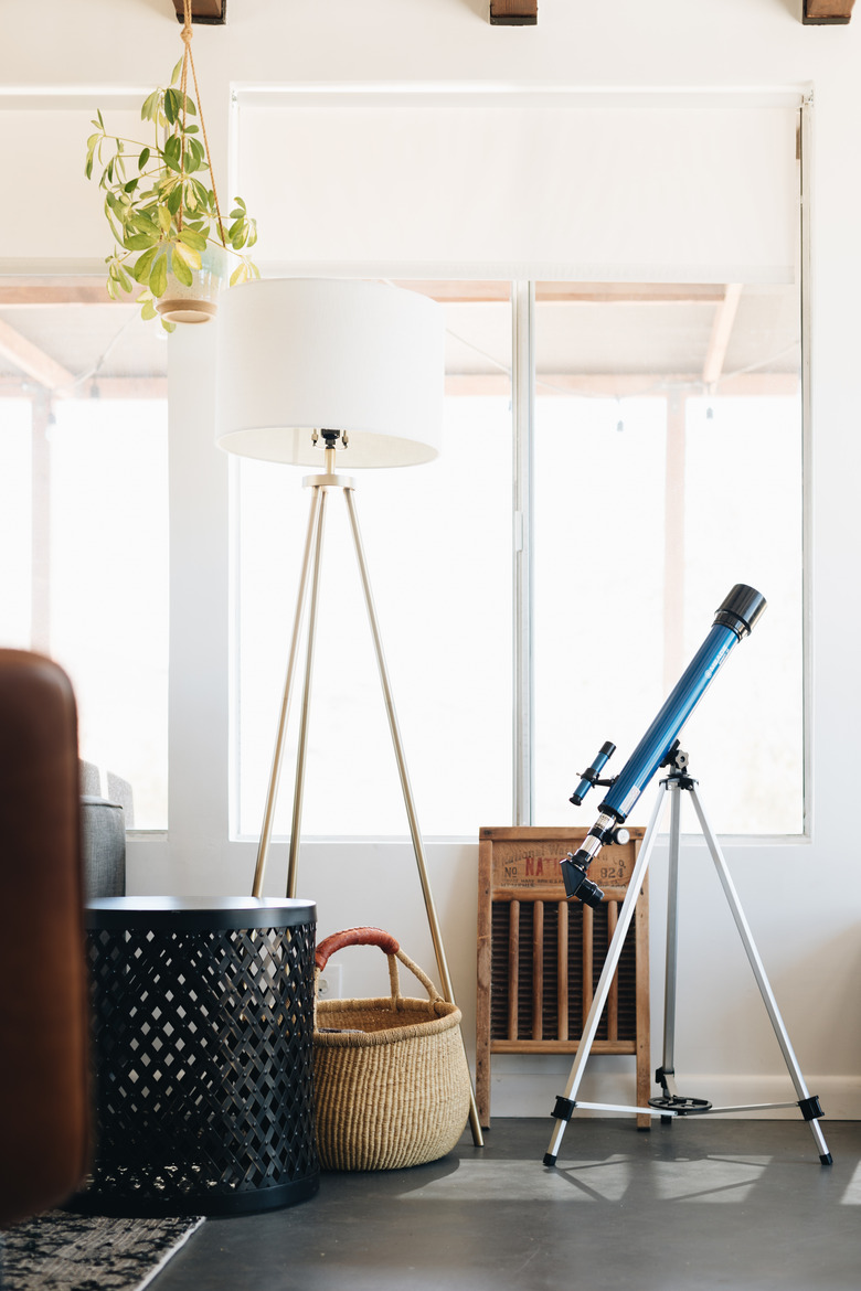 telescope in cabin living room near window and floor lamp