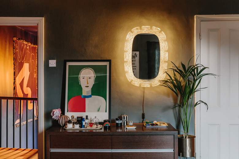 walnut console with abstract artwork and lit mirror