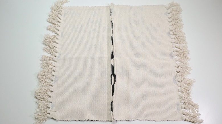 Stitching cut pieces of rug back together for zCutting excess material from fringe rug for DIY Fringe Pillow project.