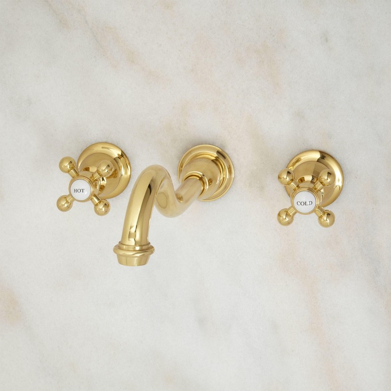 Wall-mounted brass faucet in three separate pieces with criss-cross hot/cold handles