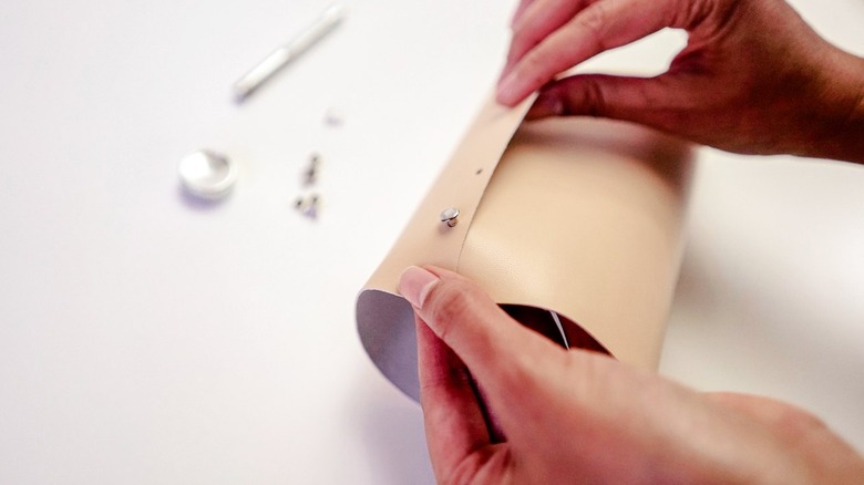 Hands folding leather with silver rivet
