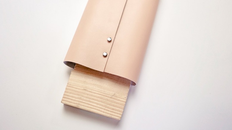 Beige leather vases with silver rivets and piece of wood