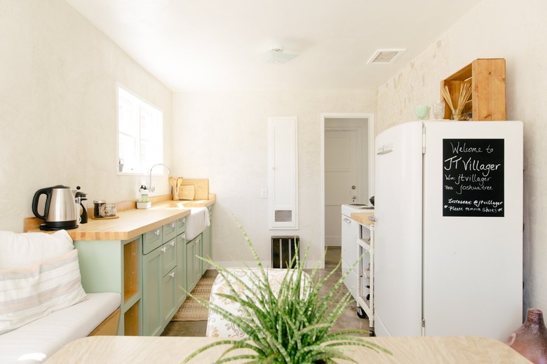 a narrow kitchen has a row of green cabinets on one wall