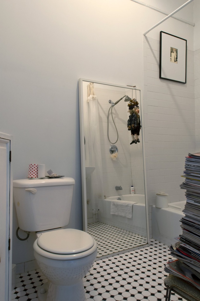 White minimalist bathroom with black and white tiled floors and books