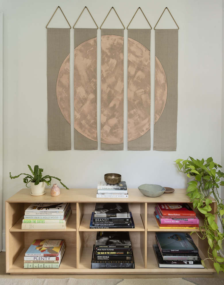 Artwork over wood shelving unit with books