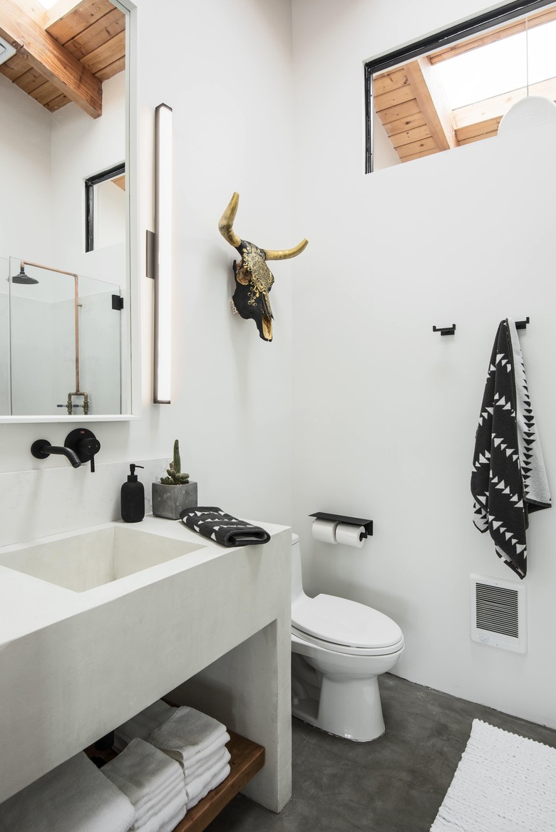 A white concrete bathroom with sink and toilet.