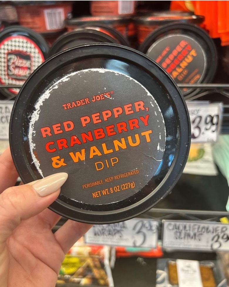 A white woman's hand holds a tub of Trader Joe's red pepper