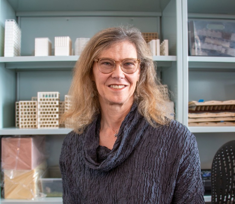 Architect Helen Bronston with shoulder-length blonde hair wearing a pair of light brown glasses and a dark blue