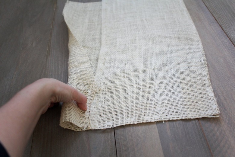 Hand folding burlap sheet to create pocket for dowel