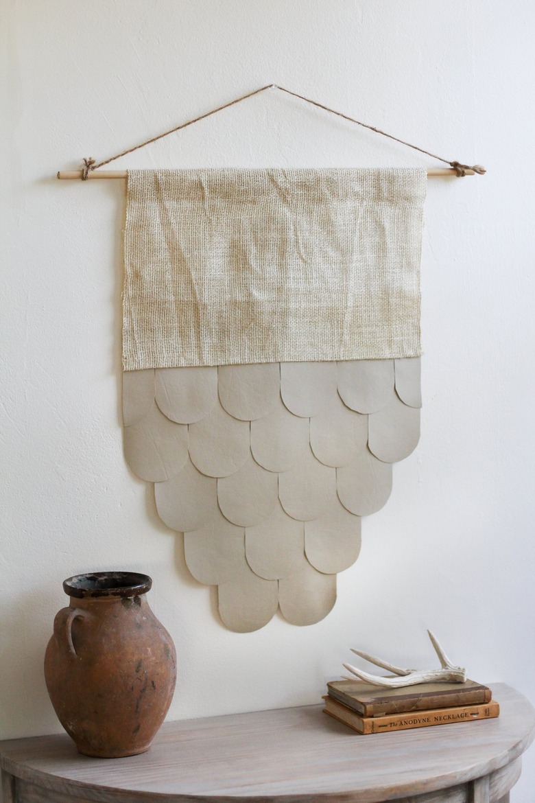 Leather-burlap wall hanging over half-moon table with decorative vase