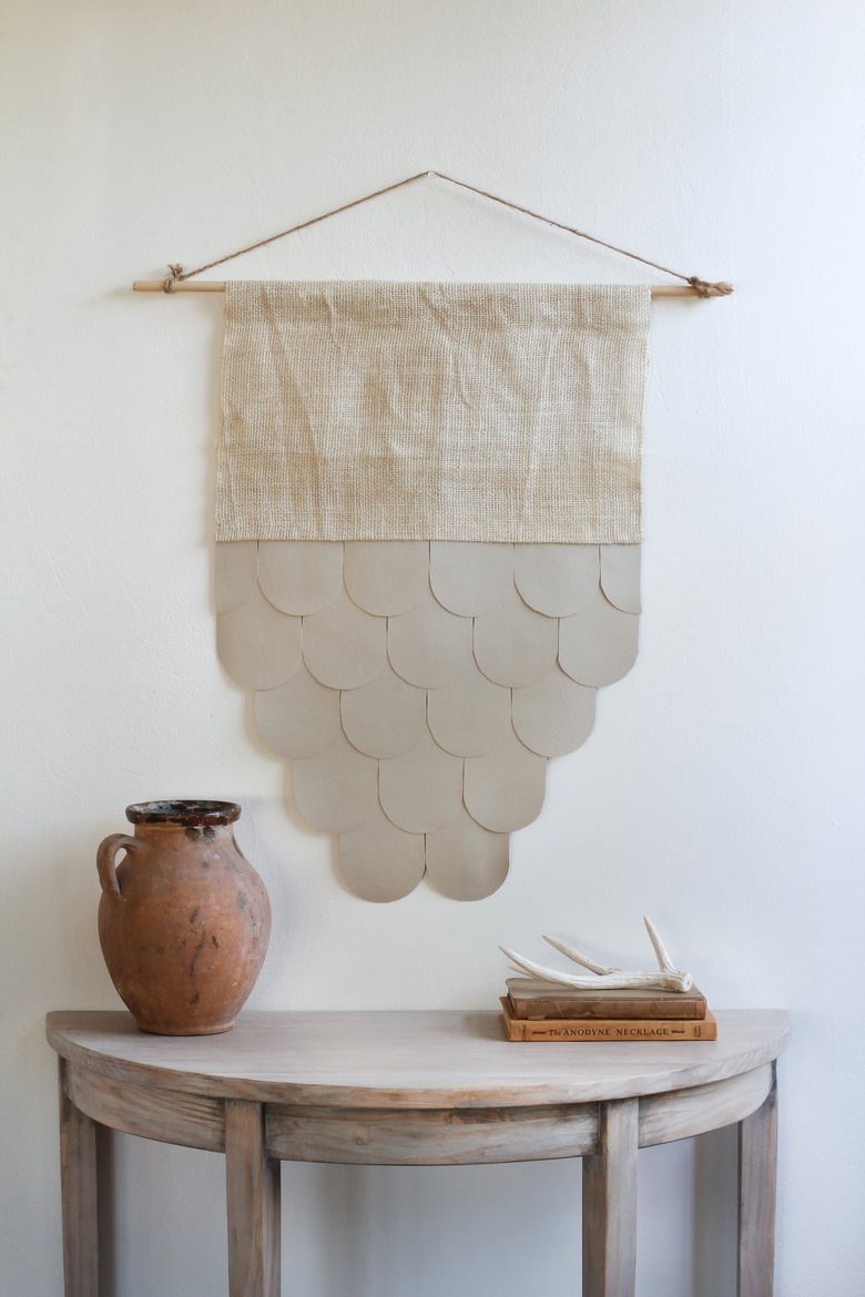 Burlap-leather wall hanging over half-moon table with decorative vase