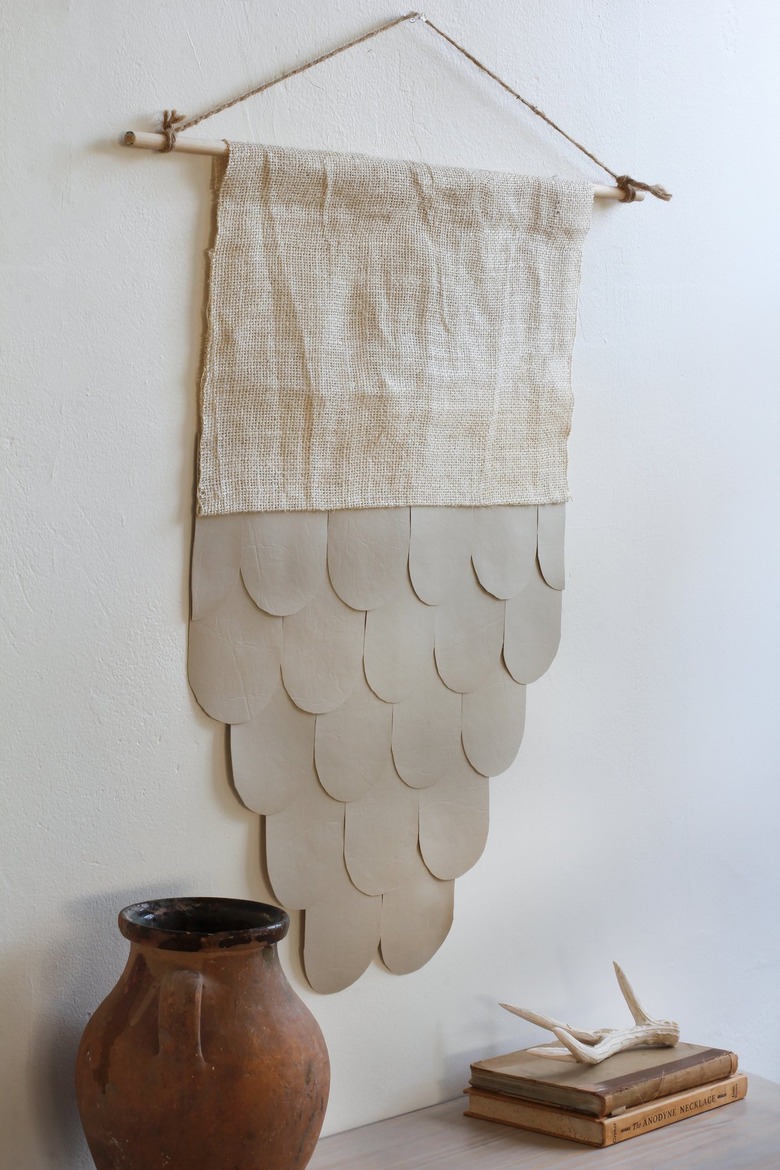 Boho leather and burlap wall hanging on white wall with decorative vase