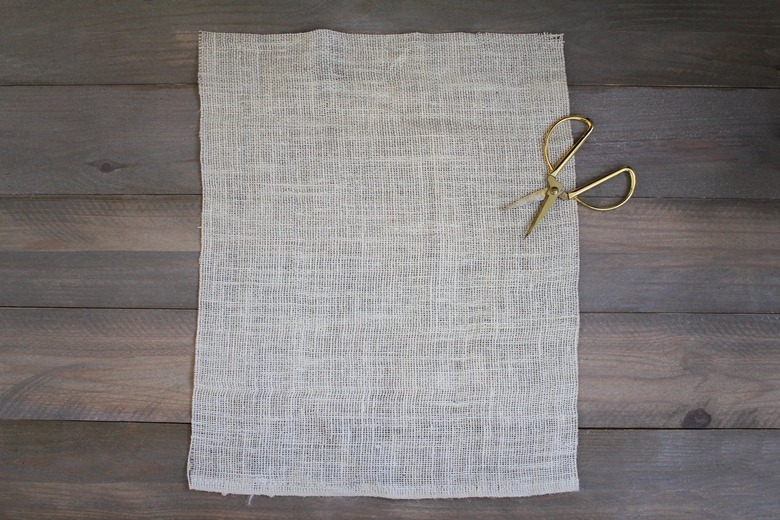 Burlap sheet wit gold scissors on wood background