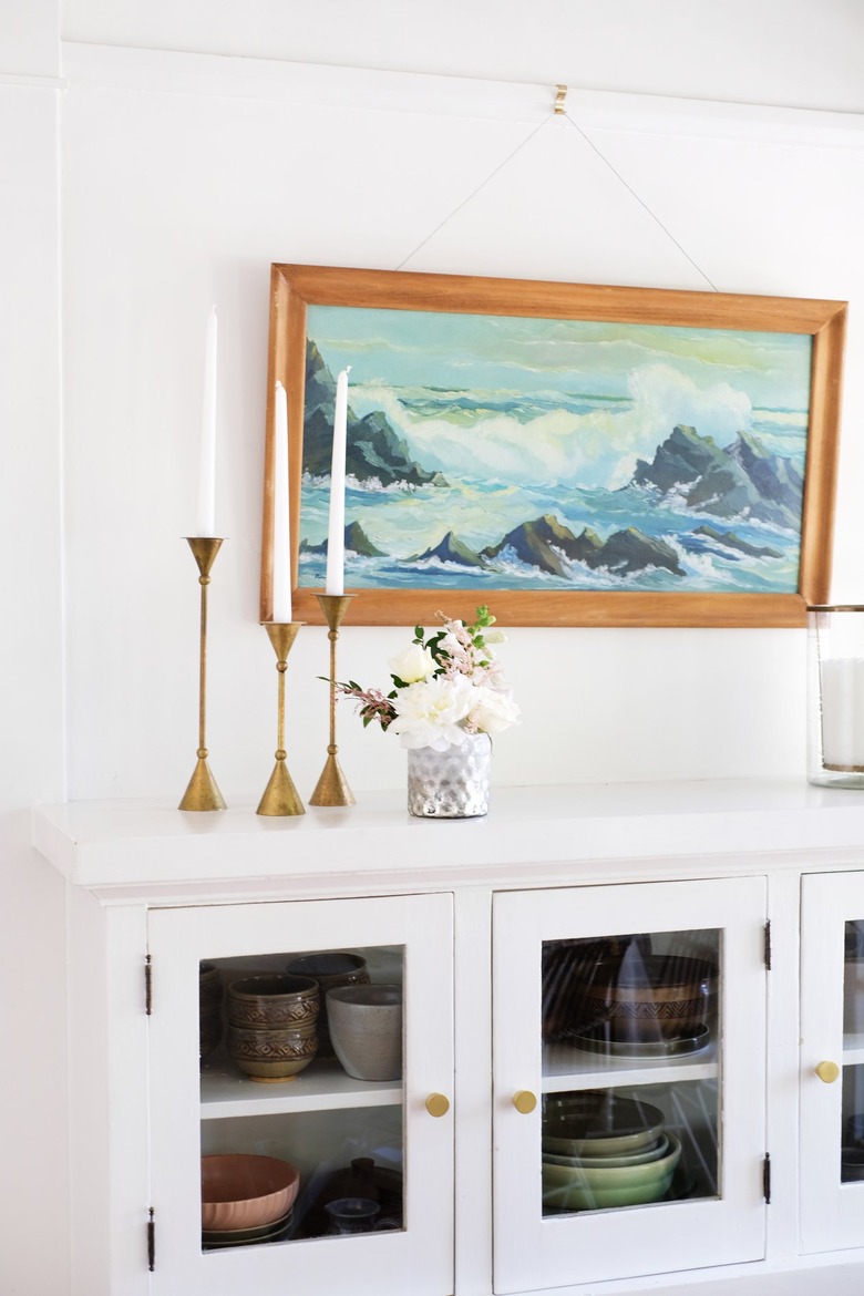White dishware cabinet with gold candlesticks