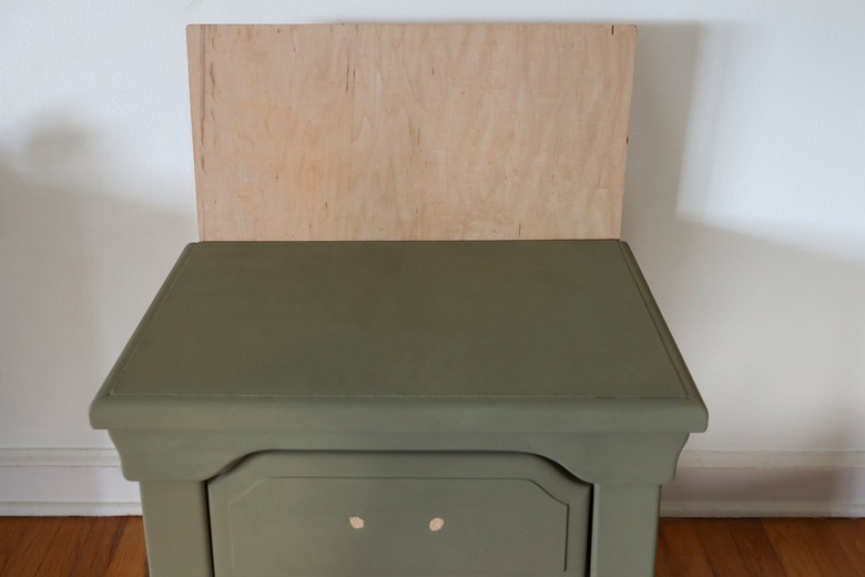 Plywood sheet attached to the back of the nightstand to create a backsplash
