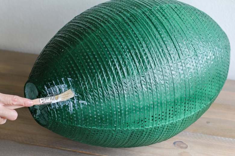 Paint brush applying adhesive on large green lantern