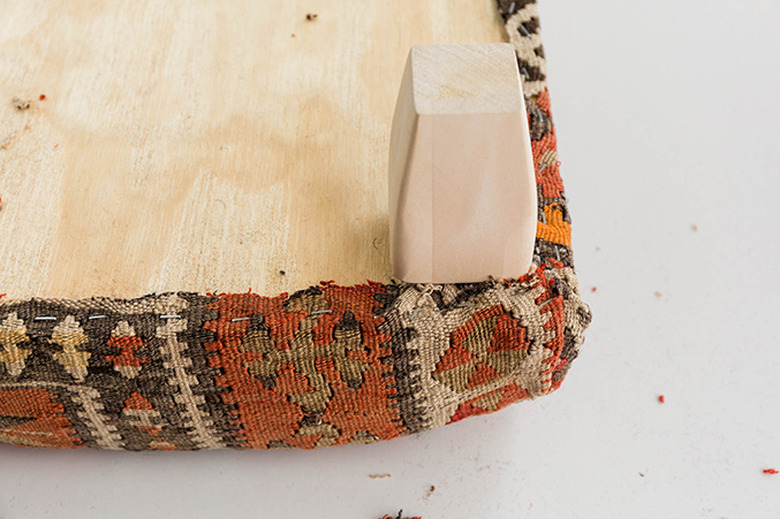 Screw the wood table legs onto the ottoman.