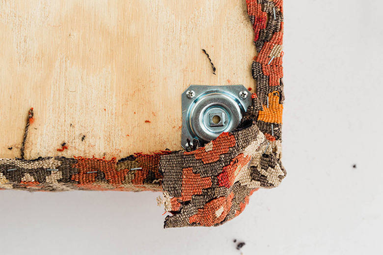 Staple the rug around the corners of the plywood board.