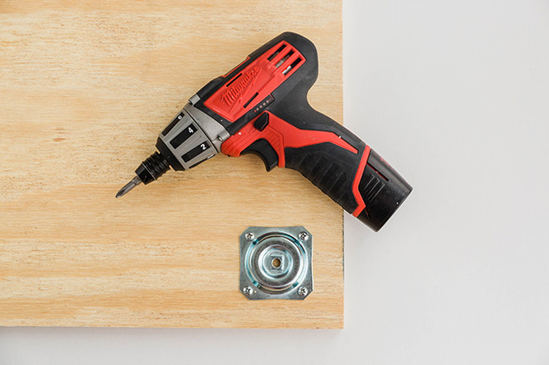 Attach the table leg plates to the corners of the plywood board.