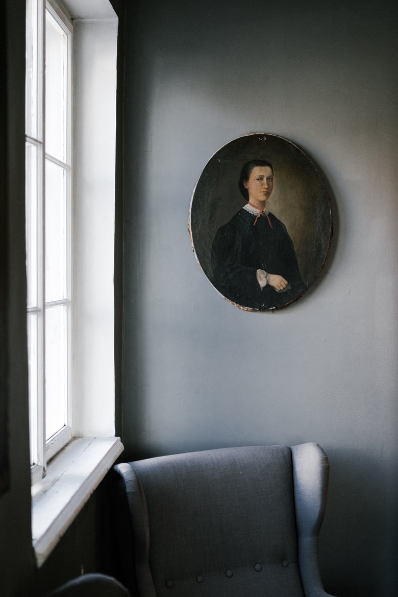 Vintage painting over gray accent chair by window