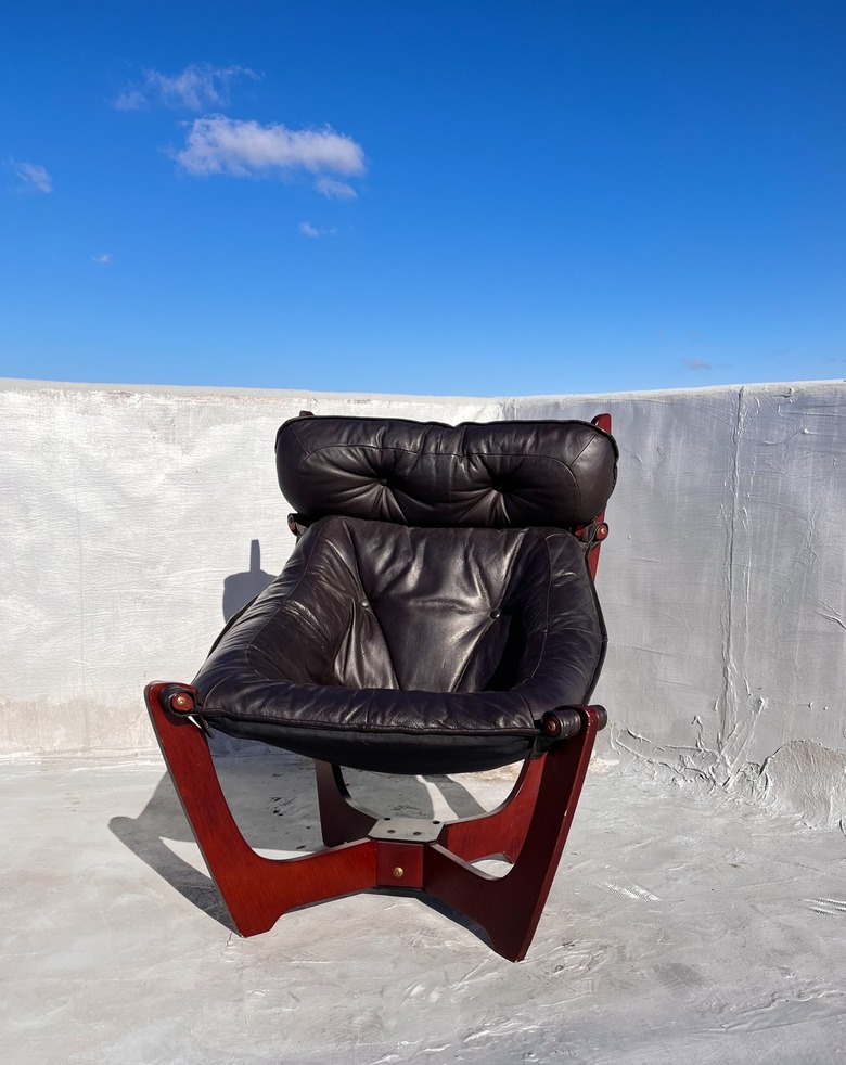 A black high-back upholstered chair with no arms and a dark wood base.