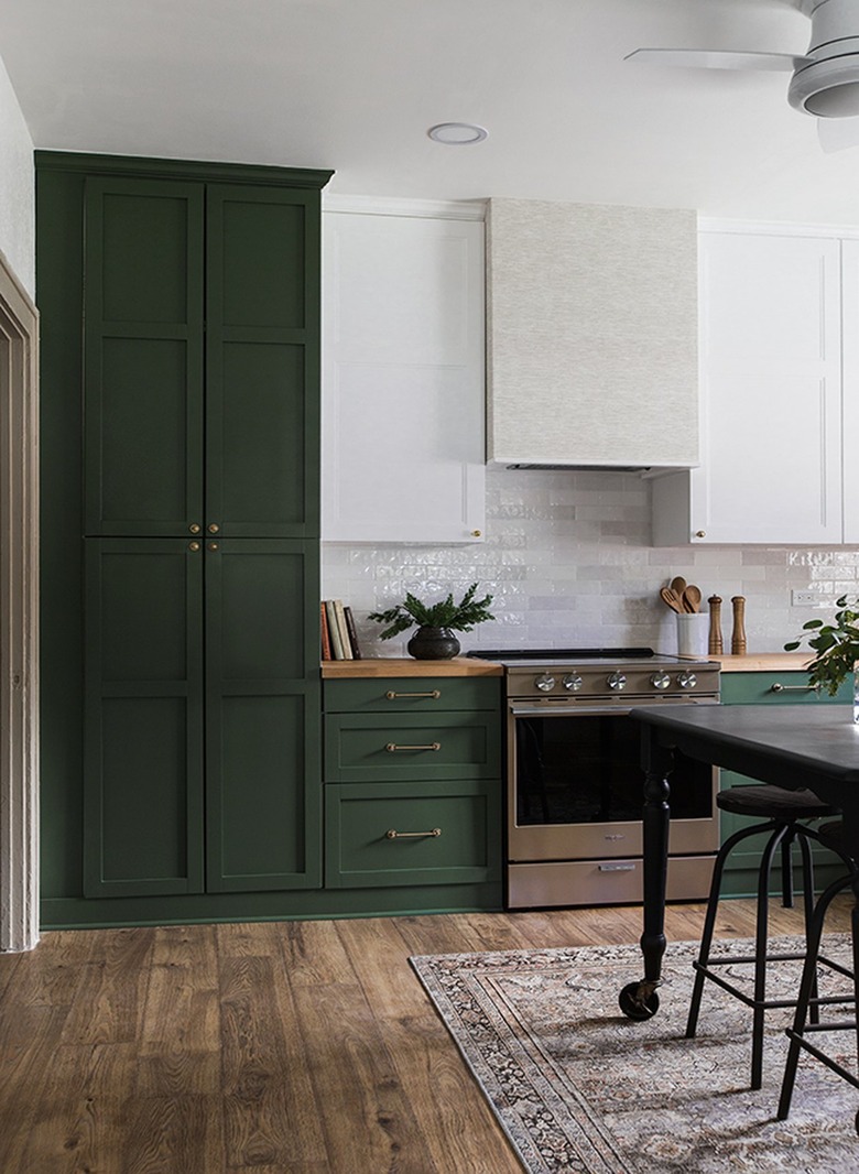 Kitchen with green cabinets and dark wood floors.