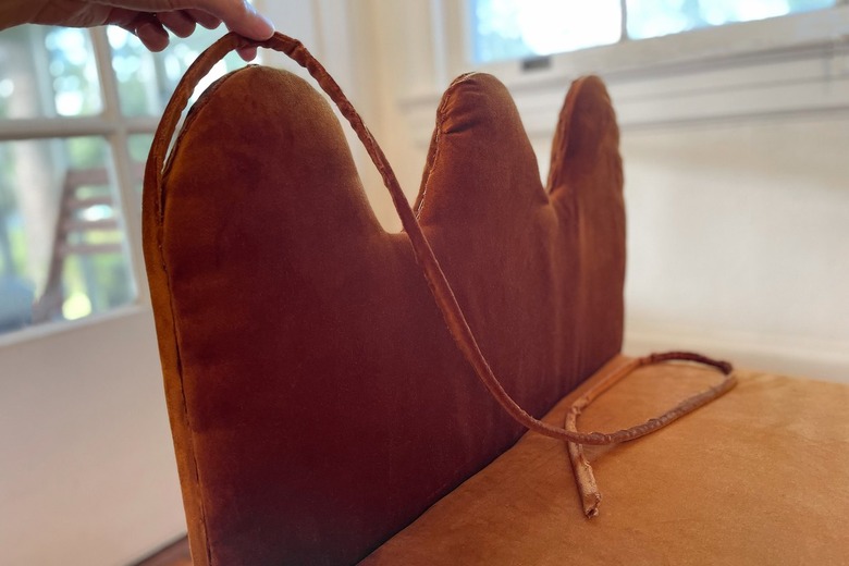 Hot gluing piping cord around the rim of the wavy bench arms to hide the staple seam