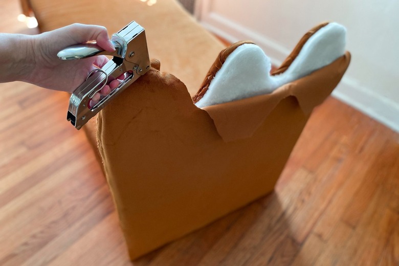 Upholstering the outer side of the wavy bench arms.