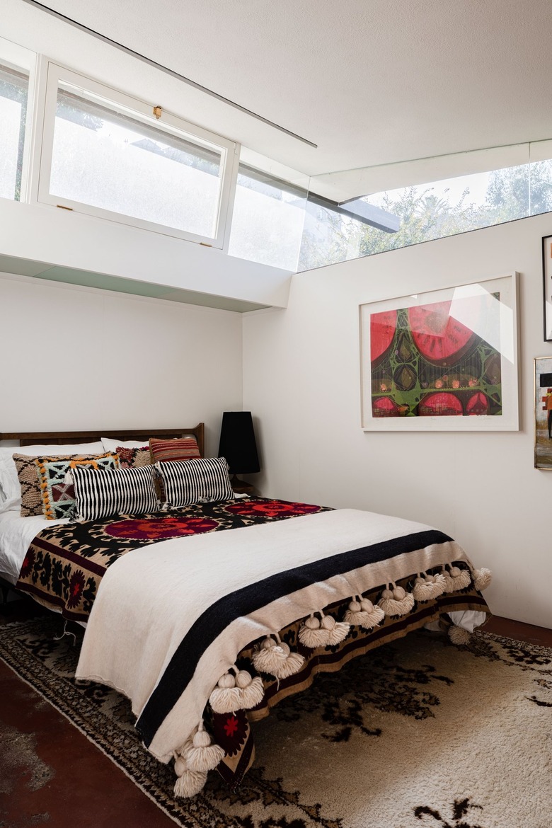 A white-walled bedroom with bohemian bedding and multiple windows