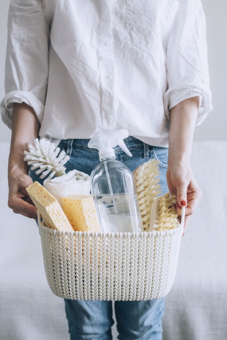 Woman holding cleaning supplies in basket