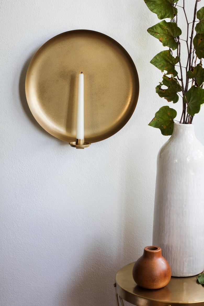 Round wall sconce with candle next to vases