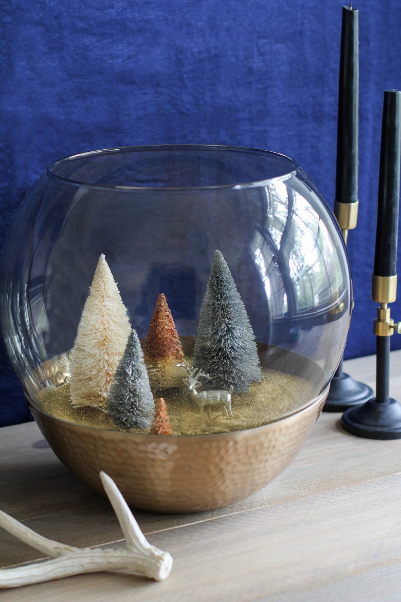 a holiday scene made from a glass lamp globe and bottle-brush trees