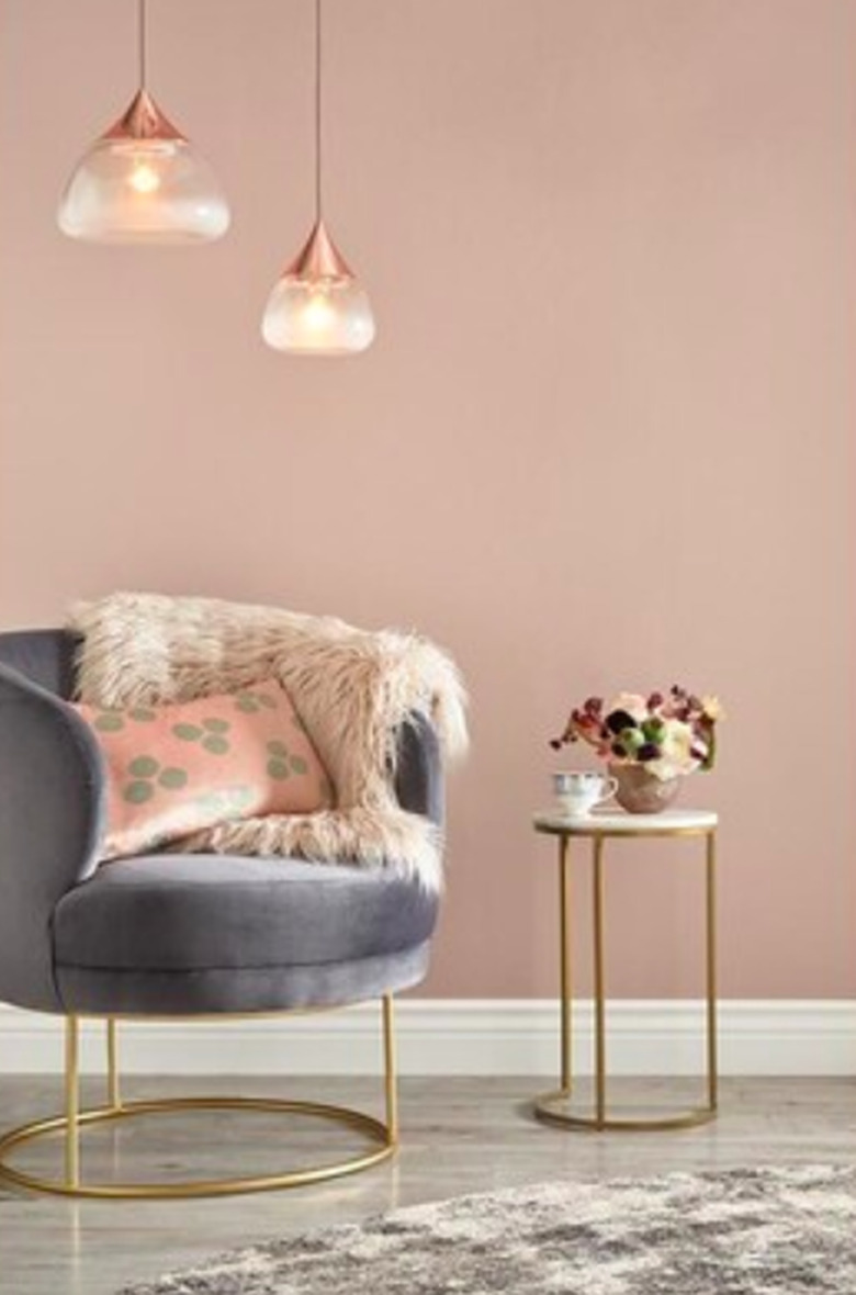 gray chair with hanging lights above it and blush wall in the background