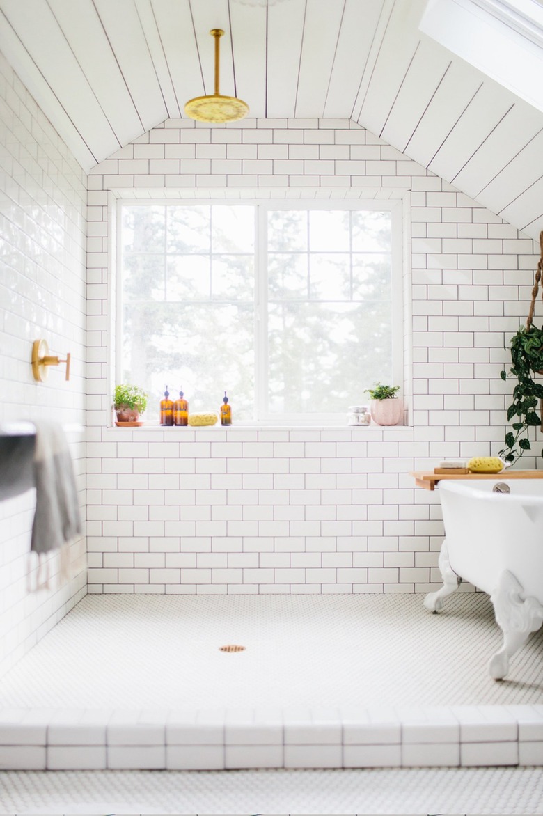 White subway tile wet room with club tub and gold accents