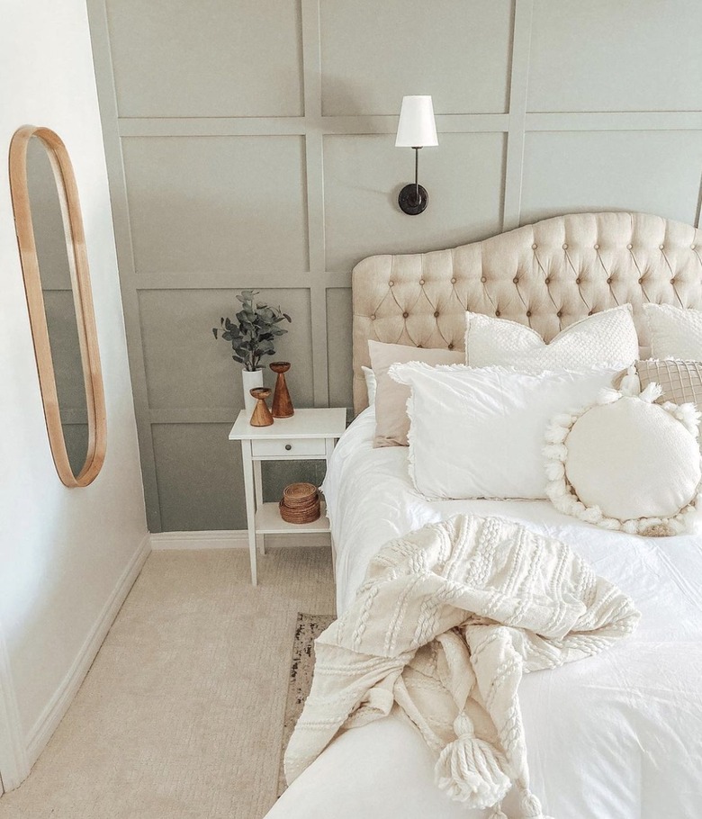 Bedroom with sage green accent wall and neutral bedding.