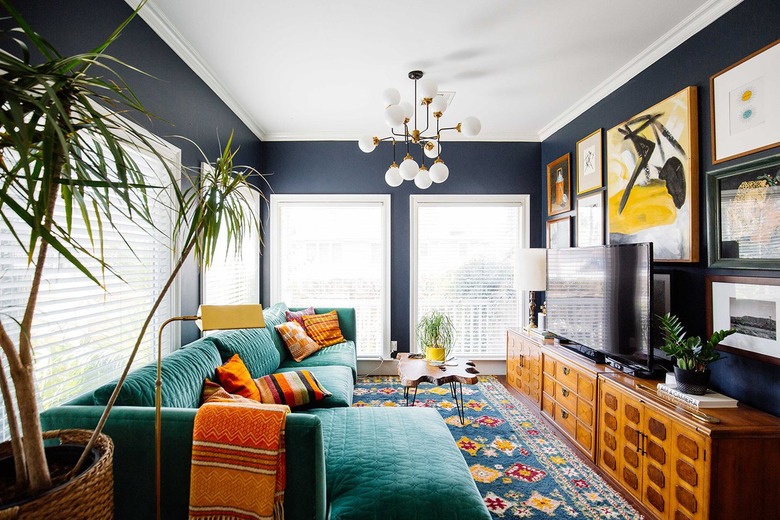 Living room with green velvet sofa and navy blue walls.