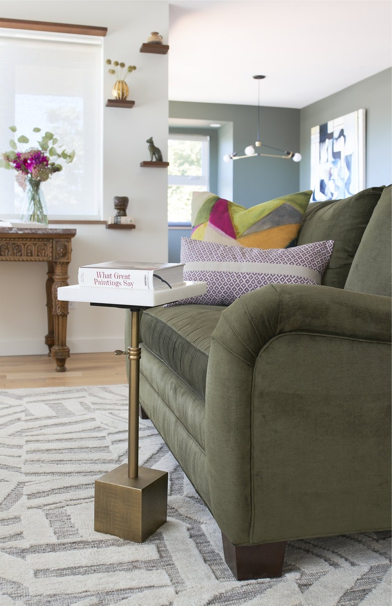 Living room with olive green couch and brass accessories