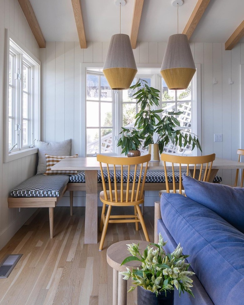 A white dining nook with yellow lamps and chairs