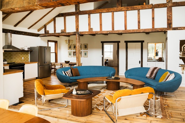 blue curved couches with a curved coffee table and midcentury chairs in a half-timbered atrium