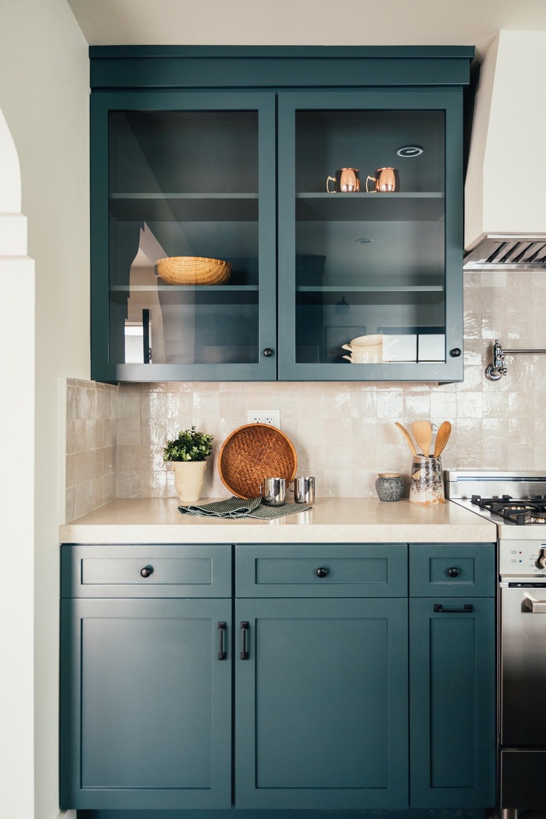 Kitchen cabinetry painted green with cream colored tiles for the backsplash.